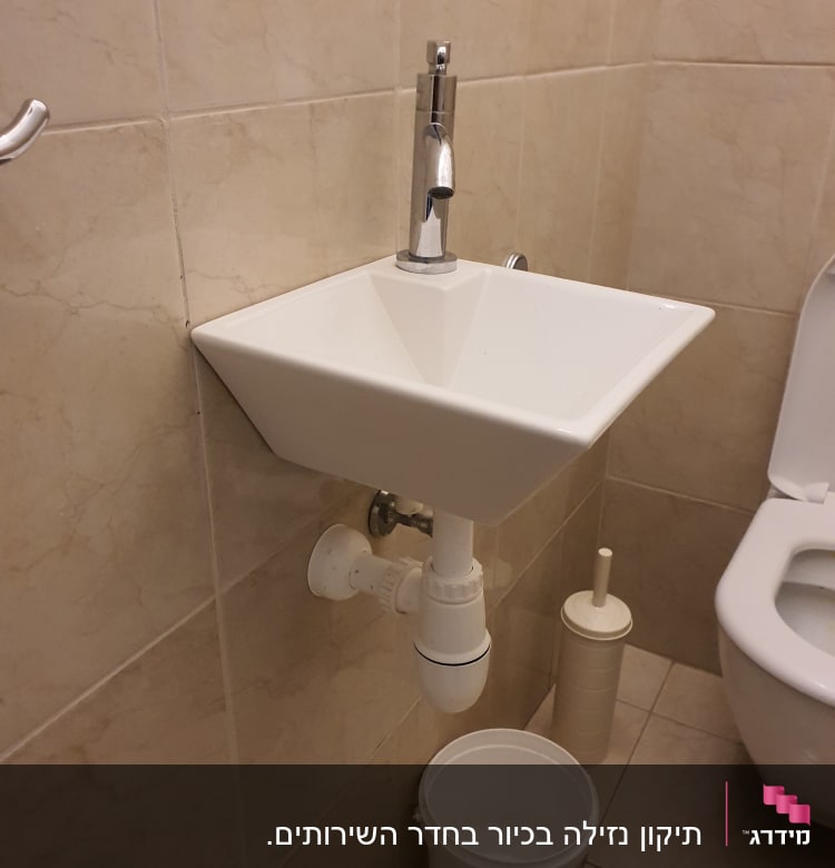 כיור עם ברז, צינור ניקוז ודלי מתחת